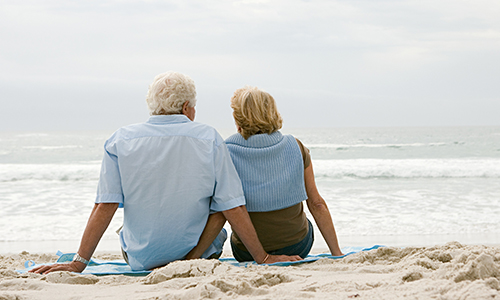 Older couple sitting on the beach looking at the Ocean